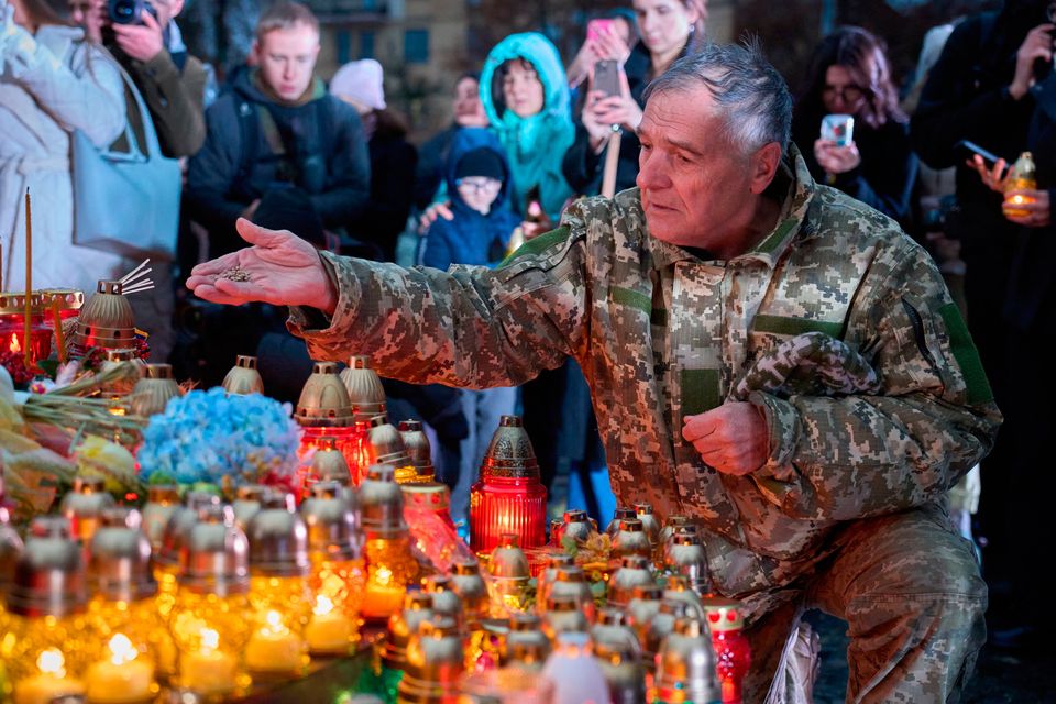 A war veteran throws seeds at the foot of the monument to victims of Holodomor, Ukraine's Great Famine, that killed millions in the 1930s. Photo: AP